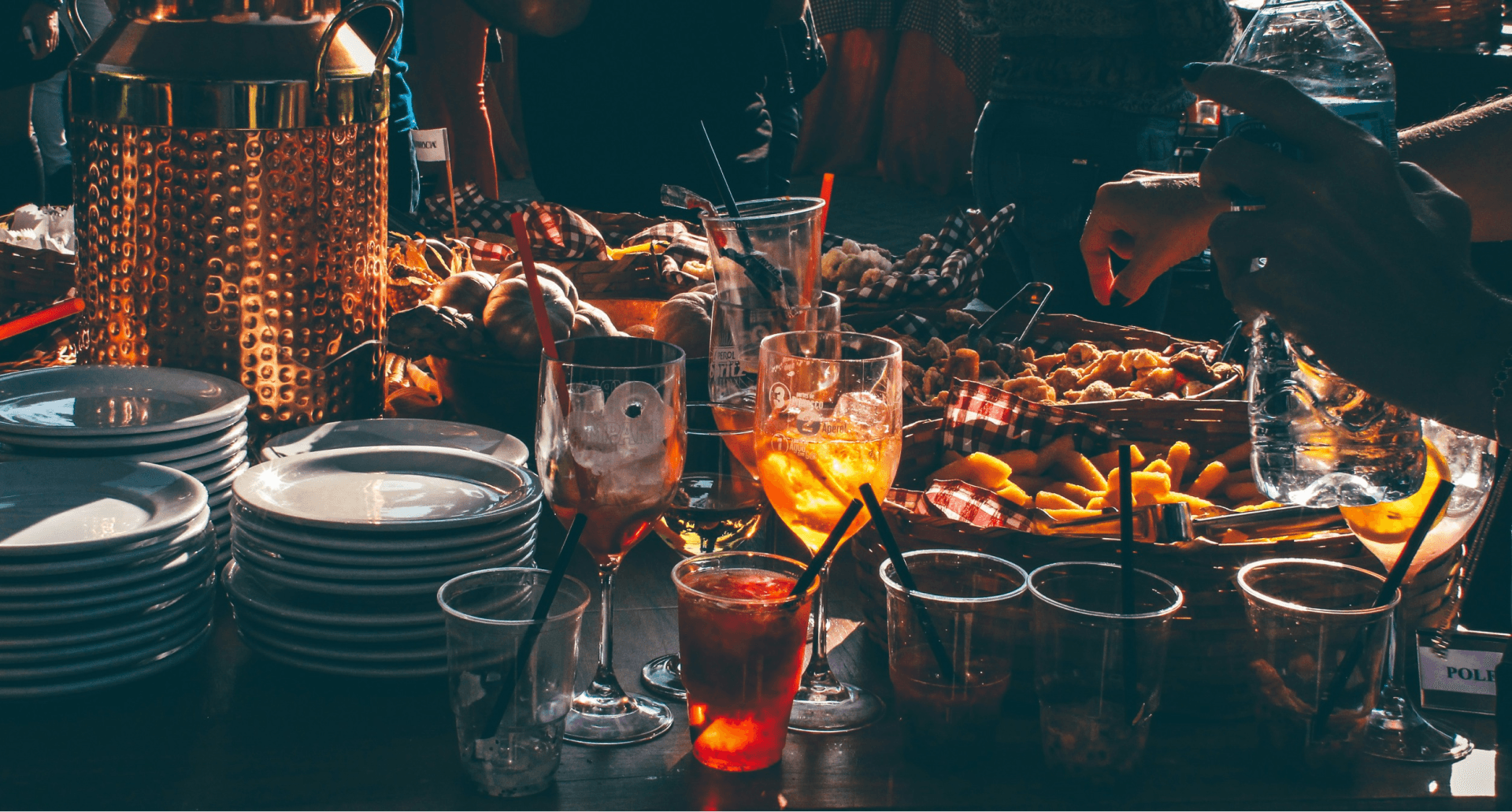 table at a party, full of party food, drinks and stacks of plates.